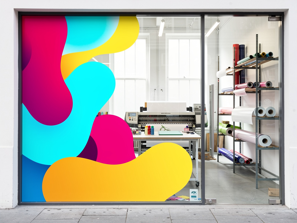 A storefront window covered in a bold colorful abstract graphic, viewed from the sidewalk in daylight.